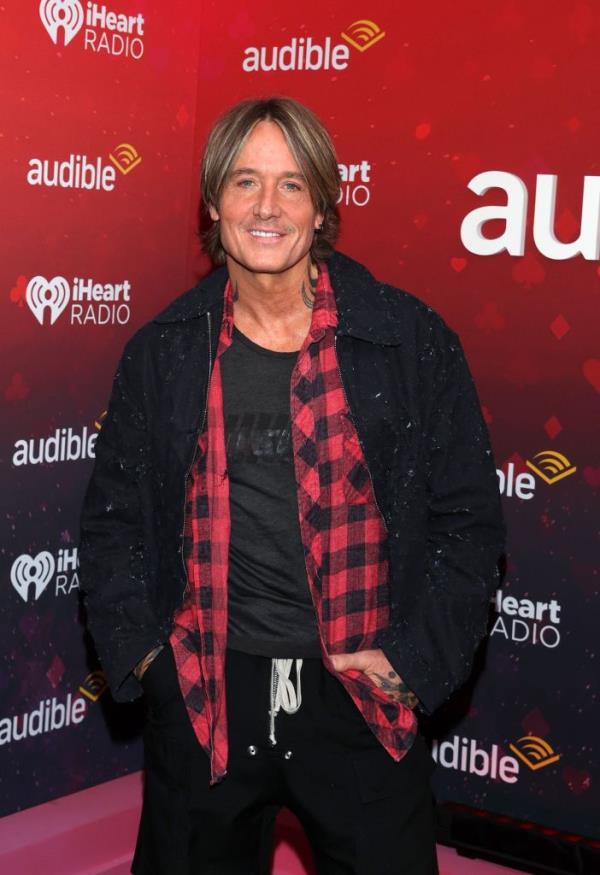 Keith Urban standing in front of a red and black wall at the 2024 iHeartRadio Music Festival in Las Vegas, Nevada