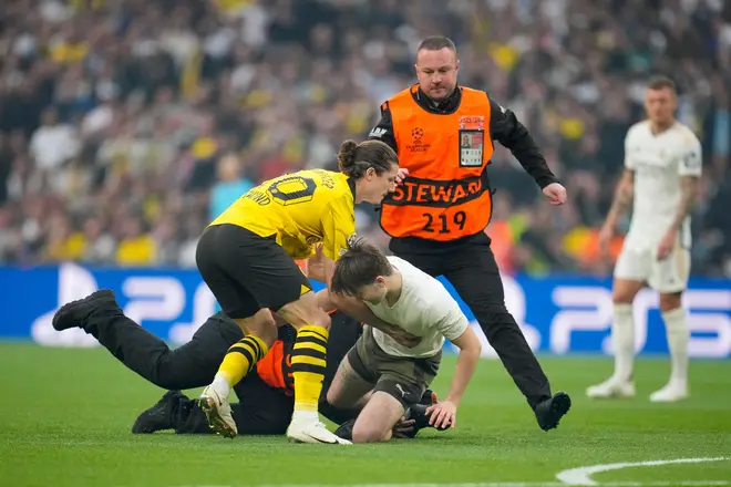 Dortmund's Marcel Sabitzer tries to hold up a pitch invader followed by security during the Champions League final soccer match between Borussia Dortmund and Real Madrid at Wembley stadium in London, Saturday, June 1, 2024. (AP Photo/Kin Cheung)